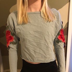 A blue shirt with red roses on the side arms.